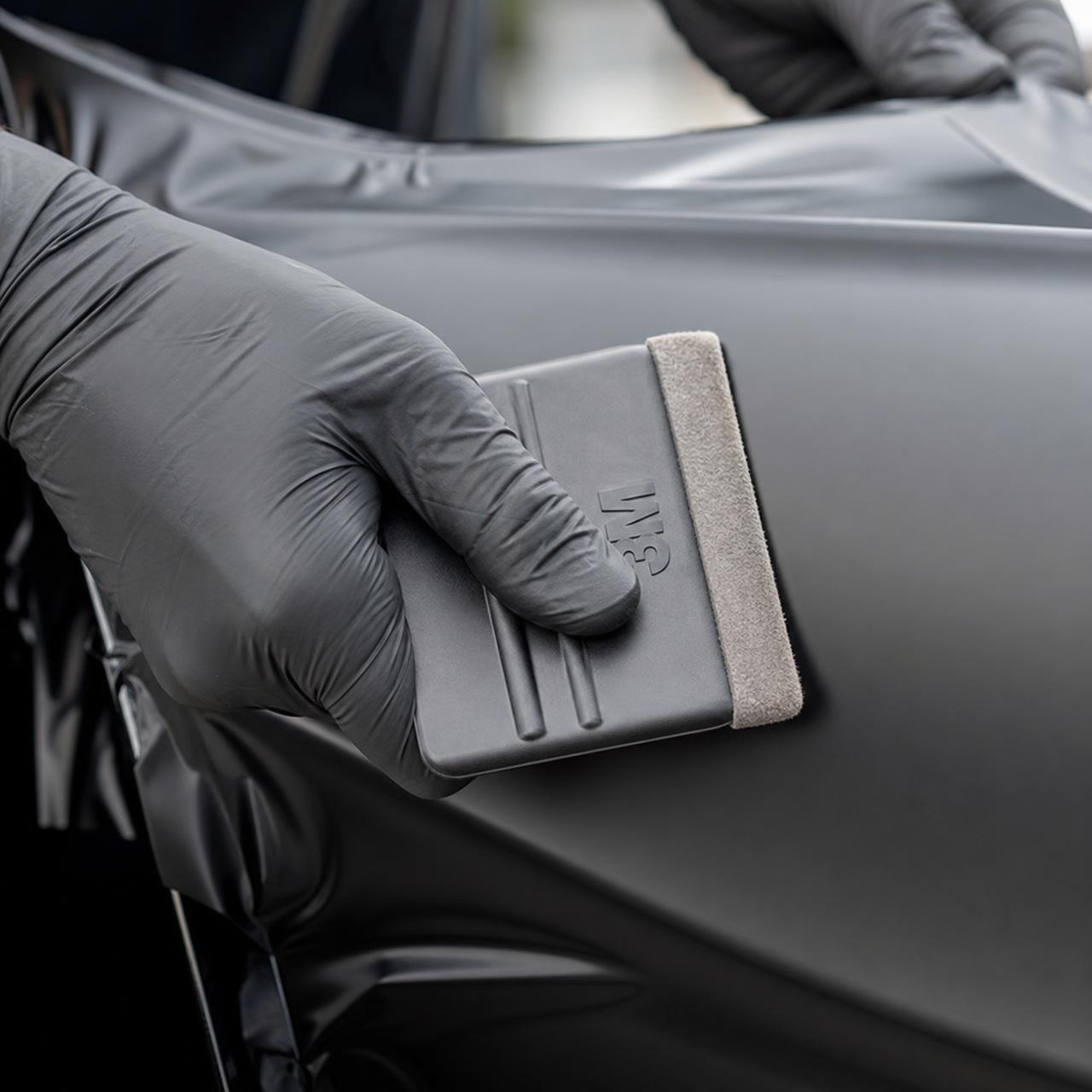 Craftsman installing vinyl wrap with squeegee